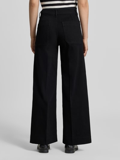 Frauenmodel trägt schwarze Wide Fit Jeans aus Baumwoll-Mix Modell 'JESSIE' von MANGO, mit aufgesetzten Taschen, Ganzkörperansicht Rückansicht.