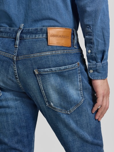 Männermodel trägt Slim Fit Jeans aus Baumwoll-Mix von Dsquared2, mittleres Blau, 5-Pocket-Design, Label-Detail, Detailaufnahme Rückansicht.