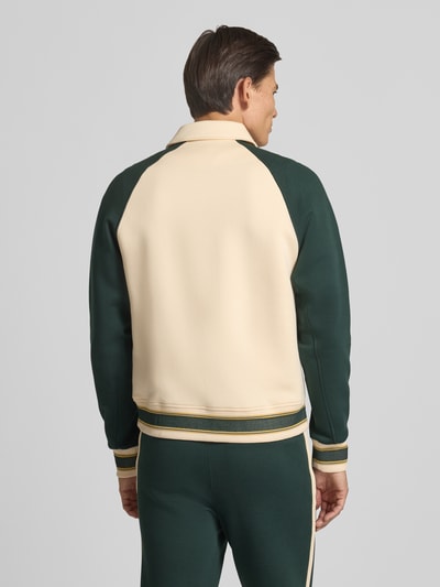 Männermodel trägt Regular Fit Sweatjacke aus Baumwoll-Mix von Lacoste in Creme und Dunkelgrün, Ganzkörperansicht Rückansicht. Herren Sweatjacke von Lacoste