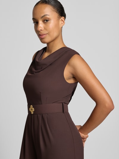 Frauenmodel trägt Jumpsuit mit Neckholder von Rinascimento in Braun, Material-Mix mit Stretch, tailliert, Stoffgürtel, Nahaufnahme Oberkörper.