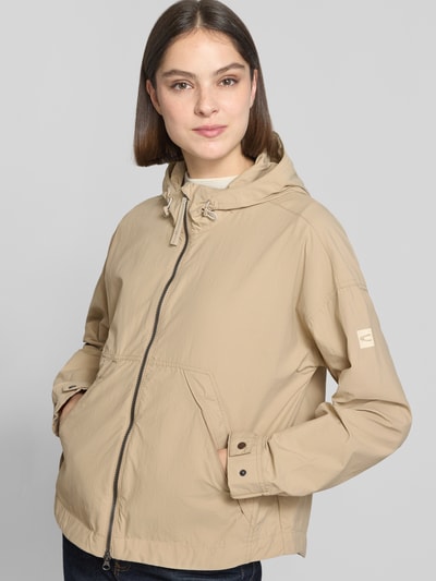 Frauenmodel trägt Jacke mit Kapuze und Zweiwege-Reißverschluss von camel active in Beige mit Seitliche Eingrifftaschen, Gerader-Schnitt, Nahaufnahme Oberkörper. Rückenlänge 67 cm, Schulterbreite 44 cm, Brustweite 63 cm, Ärmellänge 62 cm bei Größe 36.