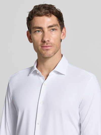 Männermodel trägt Slim Fit Businesshemd aus reiner Baumwolle Modell 'KENNO' von HUGO, weiß, glatte Textur, Nahaufnahme Oberkörper.