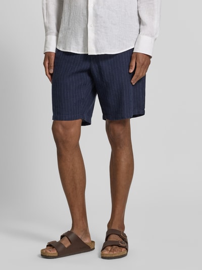 Männermodel trägt Straight Fit Leinenshorts mit Gesäßtaschen von Gant in Dunkelblau mit weißen Streifen, Reine Leinen, Elastischer Bund mit Tunnelzug, Bundweite 43 cm, Innenbeinlänge 23 cm, Ganzkörperansicht von vorne.