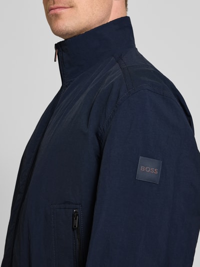 Männermodel trägt Relaxed Fit Blouson aus wasserabweisendem Material Modell 'OPENS' von BOSS Orange, Optik: Unifarben, Label-Patch, Zweiwege-Reißverschluss, gerippter Ärmelabschluss, seitliche Eingrifftaschen, Nahaufnahme Oberkörper.