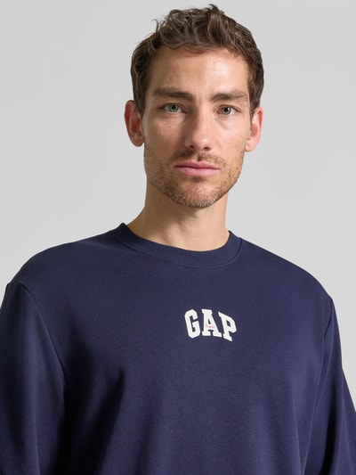 Männermodel trägt T-Shirt mit Rundhalsausschnitt und Logo-Print von GAP in Dunkelblau, Baumwoll-Mix, Loose Fit, Nahaufnahme Oberkörper.