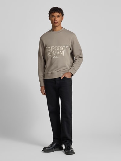 Männermodel trägt Sweatshirt mit Label-Stitching von Emporio Armani, Reine Baumwolle, Lockere-Schnitt, Gerippte-Abschlüsse, Rundhalsausschnitt, Ganzkörperansicht von vorne.