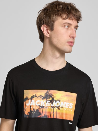 Männermodel trägt schwarzes Herren T-Shirt mit Label-Print Modell 'INDIANA' von Jack & Jones aus Reine Baumwolle, Regular-Fit, Rundhalsausschnitt, Nahaufnahme Oberkörper.