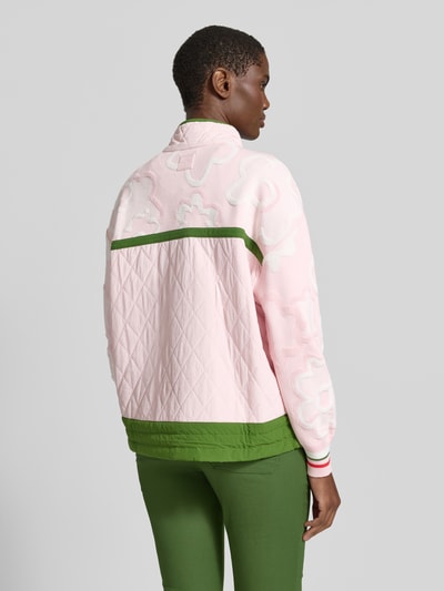 Frauenmodel trägt Relaxed Fit Pullover aus Viskose-Mix mit Troyer-Kragen von Marc Cain, rosa-grünes, florales Design, Ganzkörperansicht Rückansicht. Rückenlänge 62 cm, Ärmellänge 54 cm.