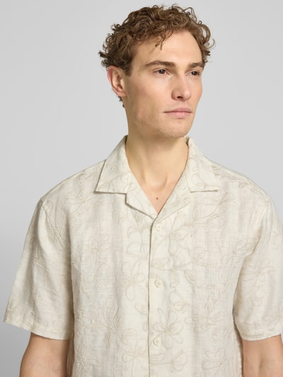 Männermodel trägt Regular Fit Freizeithemd aus reinen Leinen Modell 'ERASMUS' von JAKE*S STUDIO MEN in beige mit floralen Stickereien, Nahaufnahme Oberkörper.