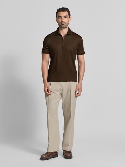 Männermodel trägt braunes Regular Fit Poloshirt aus Baumwoll-Mix Modell 'FAVE' von Selected Homme, helle Hose, Herren Poloshirt, Ganzkörperansicht von vorne.