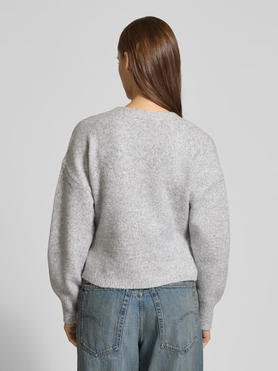 Frauenmodel trägt Regular Fit Cardigan mit Woll-Anteil Modell 'KIRA' von ONLY, melierte Strickoptik in Grau, Ganzkörperansicht Rückansicht.
