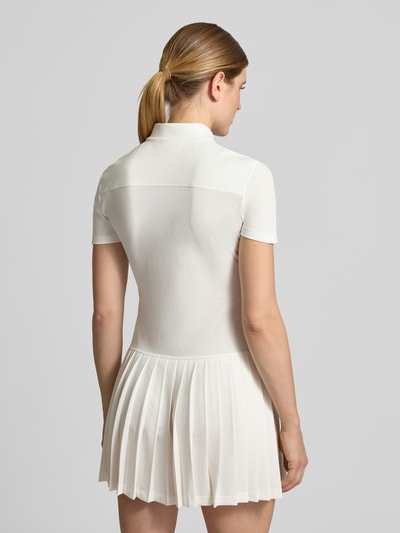 Vrouwenmodel draagt regular fit vrijetijdsjurk van katoenmix van Lacoste in effen wit met plissérok, Dames vrijetijdsjurk, volledige achterkantaanzicht