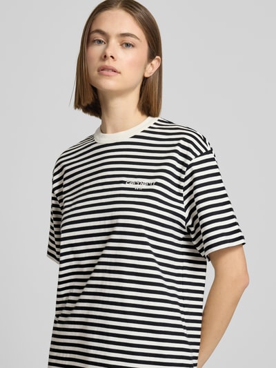 Frauenmodel trägt T-Shirt mit Label-Stitching von Carhartt Work In Progress, schwarz-weiß gestreift, reine Baumwolle, Nahaufnahme Oberkörper.