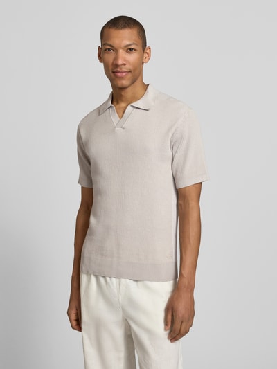 Männermodel trägt Regular Fit Poloshirt aus reiner Baumwolle Modell 'ARAVOLO' von BOSS Orange in Strickoptik mit Label Patch, Ganzkörperansicht von vorne.