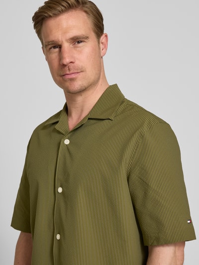 Männermodel trägt Relaxed Fit Freizeithemd aus Seersucker-Material von Tommy Hilfiger, Optik:Allover-Muster, Kurzarm, Nahaufnahme Oberkörper.