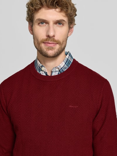 Männermodel trägt Regular Fit Pullover aus Baumwoll-Woll-Mix von GANT in Dunkelrot mit feiner Struktur, Nahaufnahme Oberkörper. Herren Pullover von GANT