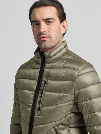 Männermodel trägt Regular Fit Steppjacke mit Stehkragen von Tom Tailor in Oliv, unifarben, mit Reißverschluss und Brusttasche, Nahaufnahme Oberkörper.