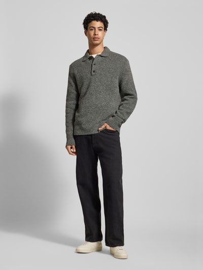 Männermodel trägt Strickpullover aus Woll-Mix mit Polokragen von Calvin Klein Jeans, Regular-Fit, Knopfleiste, Label-Detail, Ganzkörperansicht von vorne.
