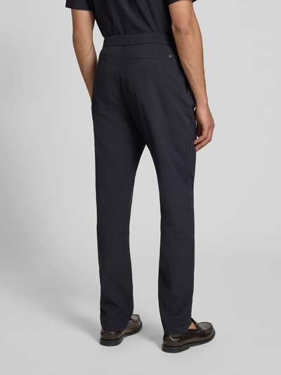Männermodel trägt Stoffhose mit elastischem Bund von Closed, dunkles Strukturmuster, Relaxed-Fit, Eingrifftaschen, Ganzkörperansicht Rückansicht.