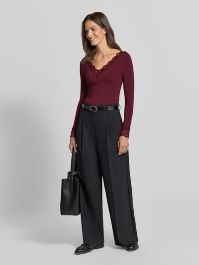 Kobiece model prezentuje bluzkę z długim rękawem Slim Fit Langarmshirt aus Modal-Mix mit Woll-Anteil Modell 'SKYE' von VERO MODA; bordowy, czarne szerokie spodnie, gładkie faktury, Ganzkörperansicht von vorne.