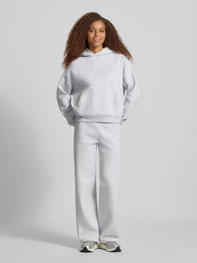 Frauenmodel trägt Sweatpants mit Häkelspitze von REVIEW, Mieszanka materiałów z mieszanką bawełny, prosty krój, elastyczny pas z tunelem, wyhaftowane logo, szydełkowa koronka, długość wewnętrzna nogawki w rozmiarze S: 79 cm, Ganzkörperansicht von vorne