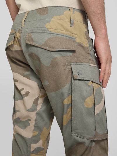 Mannenmodel draagt Tapered Cargohose aus reiner Baumwolle van g-star met all-over camouflagemotief, labelpatch, 5-pocketmodel, cargozakken, low rise band, knoop- en ritssluiting, verstelbare pijpboord, versterkte knieën, puur katoen, detailopname achterkant.