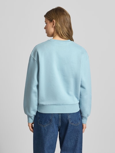 Frauenmodel trägt Sweatshirt mit Logo-Stitching Modell 'CASEY' von Carhartt Work In Progress aus Reine Baumwolle in Hellblau, Loose-Fit, mit Rundhalsausschnitt und überschnittenen Schultern, Struktur glattes Gewebe, Ganzkörperansicht Rückansicht.