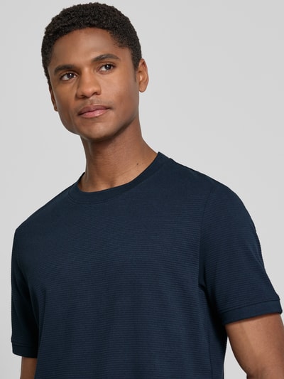 Männermodel trägt Regular Fit T-Shirt aus Baumwoll-Mix von s.Oliver RED LABEL, dunkelblau, strukturierte Textur, Nahaufnahme Oberkörper.