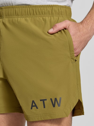 Männermodel trägt Shorts mit elastischem Bund von HALO in Olivgrün mit Label-Print, Material-Mix mit Stretch, Nahaufnahme Oberschenkel.