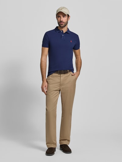 Männermodel trägt Slim Fit Poloshirt mit Logo-Stitching von Polo Ralph Lauren in Unifarben aus reiner Baumwolle, Ganzkörperansicht von vorne.