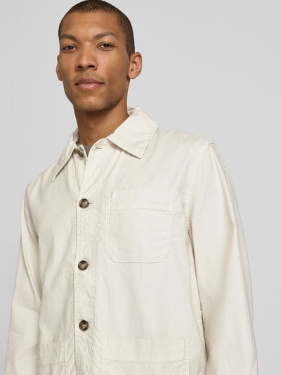 Männermodel trägt Regular Fit Hemdjacke aus Leinen-Mix von Gant in Beige mit Umlegekragen und aufgesetzter Tasche, Nahaufnahme Oberkörper.