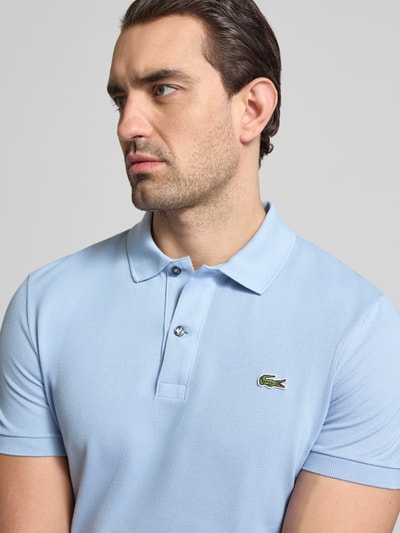 Männermodel trägt Slim Fit Poloshirt aus reiner Baumwolle von Lacoste, Optik: Unifarben, Logo-Stitching, Polokragen, Nahaufnahme Oberkörper.