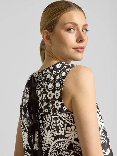 Kobiecy model nosi Boxy Fit Crop Top aus reiner Baumwolle Modell 'IFANALE' od Weekend Max Mara z florystycznym wzorem, czarno-biały, okrągły dekolt, wiązanie z tyłu, widoczne detale bawełnianej tekstury, widok z tyłu zbliżenie ramienia.