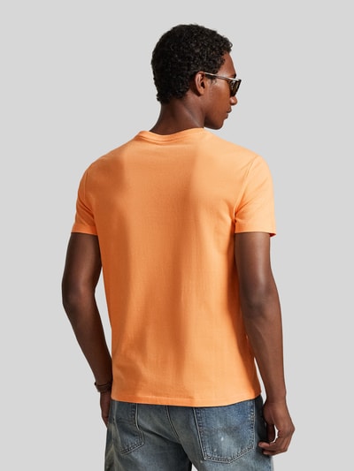 Männermodel trägt Regular Fit T-Shirt aus reiner Baumwolle von Polo Ralph Lauren, unifarben orange, Jersey, Logo-Stitching, Ganzkörperansicht Rückansicht.