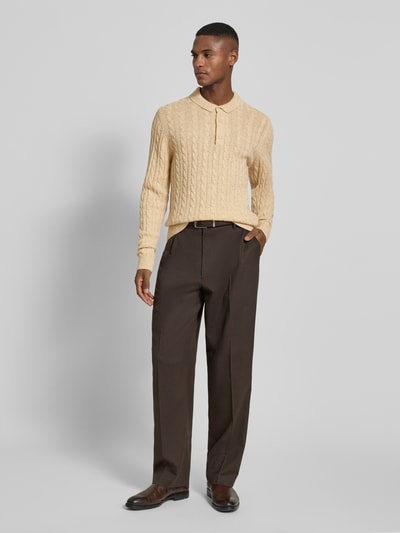 Męski model nosi Strickpullover aus Leinen-Mix mit Polokragen od Lindbergh, krój slim fit, beżowy, wzór warkoczowy, guzik przy kołnierzyku, widok całej sylwetki z przodu.