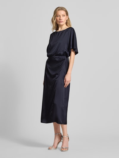 Frauenmodel trägt schimmerndes Midikleid im One-Shoulder-Look von comma in Dunkelblau, gerader Schnitt, Material-Mix, Ganzkörperansicht von vorne.