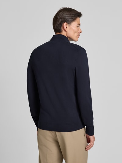 Männermodel trägt Slim Fit Strickjacke aus Viskose-Mix mit Stehkragen von MCNEAL in Dunkelblau, Ganzkörperansicht Rückansicht. Rückenlänge und Ärmellänge bei Größe M je 70 cm, elastische Abschlüsse, glatte Textur, Reißverschluss.