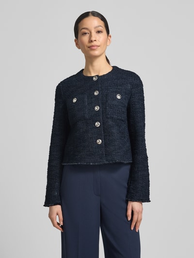 Vrouwenmodel draagt Slim Fit Blazer in bouclé-look van Betty Barclay in donkerblauw katoenmix met borstzakken en ronde hals, nahaufnahme bovenlijf. Ruglengte maat 36: 48 cm, borstwijdte: 46 cm, mouwlengte: 58 cm.