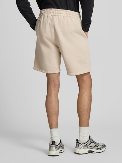 Männermodel trägt Regular Fit Shorts mit Logo-Stitching von Pegador aus Baumwoll-Mix in Beige, elastischer Bund, Ganzkörperansicht Rückansicht.