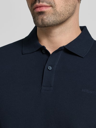 Männermodel trägt Regular Fit Poloshirt aus reiner Baumwolle von s.Oliver RED LABEL in Dunkelblau, Nahaufnahme Oberkörper.