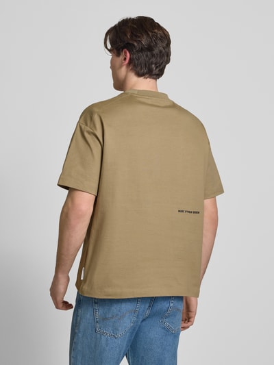 Männermodel trägt Boxy Fit T-Shirt aus reiner Baumwolle von Marc O'Polo Denim, Optik: Unifarben, Passform: Boxy-Fit, Label-Print, Rundhals, Ärmelform: Kurzarm, Farbe Beige, Material reine Baumwolle, Ganzkörperansicht Rückansicht.