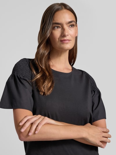 Frauenmodel trägt Regular Fit T-Shirt mit Smok-Detail von Comma aus reiner Baumwolle mit ausgestellten Ärmeln, Nahaufnahme Oberkörper.