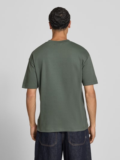 Männermodel trägt Relaxed Fit T-Shirt aus reiner Baumwolle von Marc O'Polo Denim in Olivgrün, glatte Oberfläche, Ganzkörperansicht Rückansicht. Herren T-Shirt