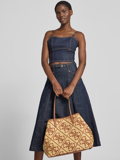 Frauenmodel trägt 2-in-1-Shopper mit Logo-Muster Modell 'KIRSTEN LARGE' von GUESS im Allover-Look mit Schulterriemen, Ganzkörperansicht von vorne.