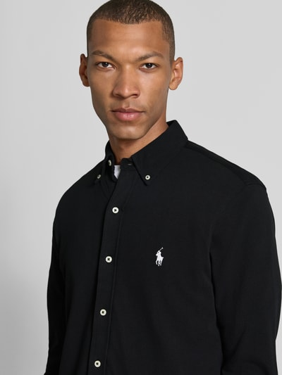 Männermodel trägt Regular Fit Freizeithemd aus reiner Baumwolle von Polo Ralph Lauren in Schwarz mit weißen Knöpfen, Nahaufnahme Oberkörper.