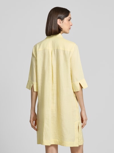 Frauenmodel trägt Knielanges Hemdblusenkleid aus Leinen mit 3/4-Arm von Christian Berg Woman in Hellgelb, Struktur aus reinem Leinen, A-Linie, verdeckte Knopfleiste, Hemdblusenkragen, Rückenlänge 96 cm, Brustweite 54 cm, Ärmellänge 41 cm, Ganzkörperansicht Rückansicht.