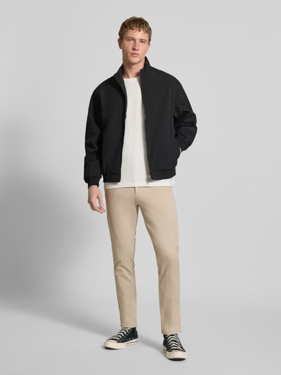 Männermodel trägt Regular fit Jack met opstaande kraag Model 'Charge' van JACK & JONES, zwart, met ritssluiting en steekzakken, elastische boorden, ruglengte maat M 66 cm, schouderbreedte 49 cm, borstwijdte 50 cm, mouwlengte 64 cm, ganzkörperansicht van voren.