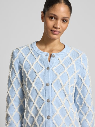 Vrouwenmodel draagt gebreid jack uit katoenmix model 'ZIGLY' van YAS in lichtblauw met witte siergarnering, ronde hals, tricotlook, ribboorden; context: dames gebreid jack, los model, ruglengte maat S 57 cm, mouwlengte maat S 71 cm; Nahaufnahme bovenlichaam.