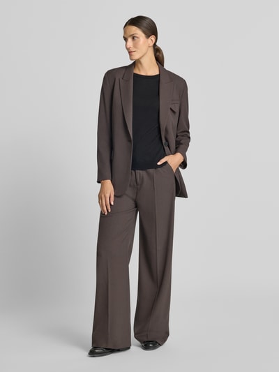 Frauenmodel trägt Relaxed Fit Anzughose mit Viskose-Anteil Modell 'TAILOR' von Cph Muse in Braun, weiter Schnitt, Kellerfalten, Ganzkörperansicht von vorne.