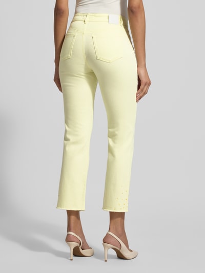 Männermodel trägt Slim Fit Jeans mit Fransen von Marc Cain, bawełna z elastanem, krój slim fit, kieszenie, szerokość w rozmiarze 36: 38 cm, długość wewnętrzna w rozmiarze 36: 70 cm, jasny żółty kolor, tekstura gładka, całkowity widok z tyłu.